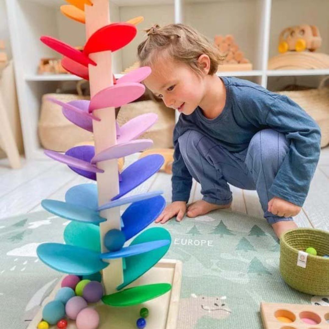 Kind spielt mit buntem Holz-Murmelbaum, Montessori-Spielzeug, pädagogisches Lernspielzeug.